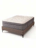 A mattress on a low upholstered bed frame with dark legs, photographed on a clean white studio background. The mattress has a quilted off-white top and a gray quilted side, while the bed base is taupe-brown.
